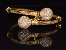 A yellow metal bangle with rope twist decoration and two spheres set with cubic zirconia, 27.3g, 5.8