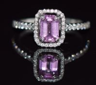 A platinum ring set with a 1ct emerald cut natural pink sapphire surrounded by diamonds, with