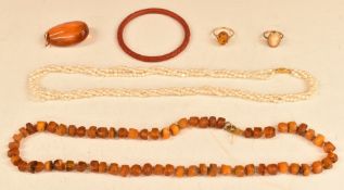 A 9ct gold ring set with a pressed amber cabochon, amber necklace, three strand pearl necklace,