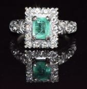 An 18ct white gold ring set with an emerald cut emerald and diamonds in a rectangular setting with