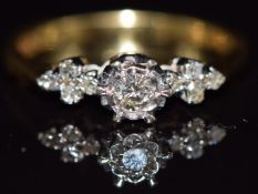 An 18ct gold ring set with a diamond, and four further diamonds to each shoulder, 3.6g, size P
