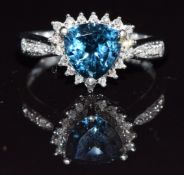 A 9k white gold ring set with a trilliant cut blue topaz surrounded by white topaz, 3.5g, size P