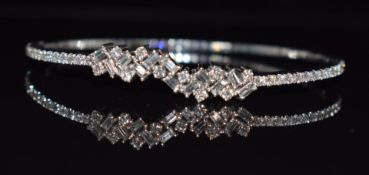 An 18ct white gold bangle set with emerald cut and round cut diamonds, 15g, 5.7 x 4.8cm