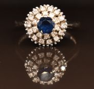 An 18ct gold ring set with a sapphire surrounded by two rows of diamonds, 4.7g, size M