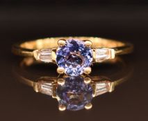 An 18ct gold ring set with a round cut tanzanite and baguette cut diamonds, 2.9g, size M