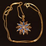 An 18ct gold pendant in the form of a star set with a diamond and blue paste with filigree