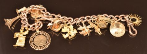 A 9ct gold charm bracelet with fifteen 9ct & 18ct gold charms including flower, Eiffel Tower,
