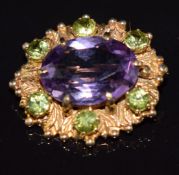 A 9ct gold brooch set with an oval cut amethyst and peridot, 6.9g, 2.5 x 2.2cm