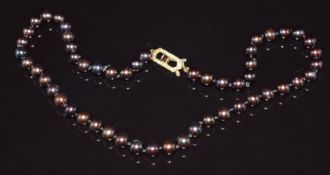 A single strand of black pearls, the yellow metal clasp set with a garnet, 40cm long