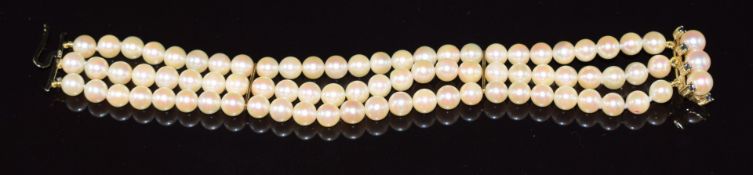 A three strand pearl bracelet, the 9ct gold clasp set with pearls and eight sapphires, 30g, 17cm