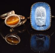 A 14k gold ring set with a tiger's eye cabochon (3.7g, size O) and a yellow metal ring set with