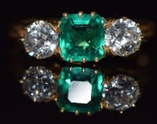 An 18ct gold ring set with an emerald cut emerald of approximately 1ct and two diamonds each