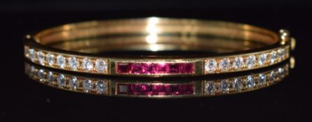 An 18k gold bangle set with round cut diamonds and square cut rubies, 21.1g, 4.8 x 5.8cm