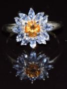 A 9k gold ring set with a round cut citrine surrounded by marquise cut tanzanites in a flower