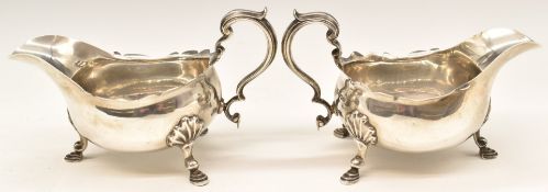 Pair of George V hallmarked silver sauce boats with shaped edges and scrolling handles, raised on