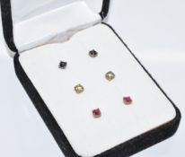 Three pairs of 9ct gold earrings set with ruby, sapphire and green sapphires