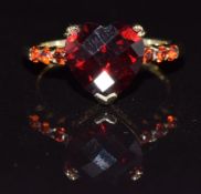 A 9ct gold ring set with a heart cut garnet and further garnets to the shoulders, 3.2g, size M