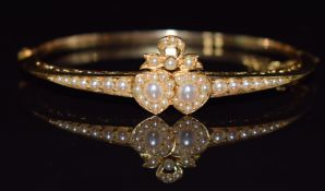 Edwardian 9ct gold bangle set with split and seed pearls in the form of two hearts and a bow in