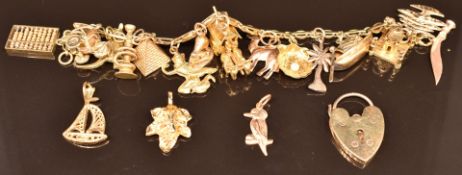 A 9ct gold charm bracelet with nineteen 14k, 9ct & 18k gold charms including pyramid, camel,