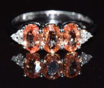 A 9k white gold ring set with three oval cut colour-change padparadscha sapphires and diamonds, 2.