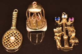 Three 9ct gold charms or pendants comprising a bird in a cage, a tennis racket set with a pearl