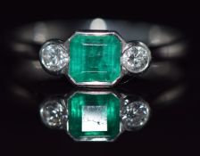 A platinum ring set with an octagonal emerald of approximately 0.65ct and two diamonds each