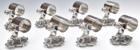 Set of eight silver plated napkin rings formed as cherubs carrying the rings, height 9cm
