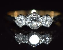An 18ct gold ring set with three diamonds in a platinum setting, the centre diamond approximately