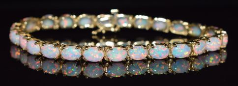 A 14k gold tennis bracelet set with synthetic oval opal cabochons, 18cm long, 15.5g