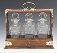 19th or early 20thC three bottle tantalus with silver plated mounts and cut glass bottles, L35cm