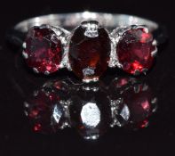 An 18ct white gold ring set with three garnets in a platinum setting, 3.2g, size M