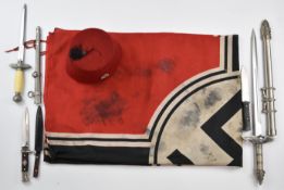 Reproduction items comprising German flag, fez hat and four daggers, longest 57cm