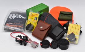 A collection of shooting and gun accessories including scope mounts, lens covers, rifle cartridge