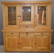A contemporary light oak glazed dresser, the top having three glazed cupboards with adjustable
