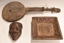Three African carved wooden tribal items including a stringed instrument with mask decoration,