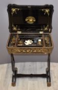 Chinese 19thC lacquered games table decorated in gilt with figural scenes, the top opening to reveal