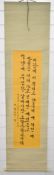 Korean scroll painting with black script on yellow ground, 135 x 33cm