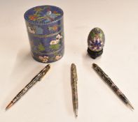 Five Chinese cloisonné items comprising a sectional pot, an egg and three pens.