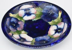 Moorcroft pedestal shallow dish decorated in the Pansy pattern on a blue ground, impressed 'Potter