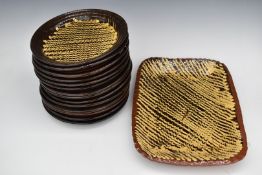A set of fourteen studio pottery slipware dinner plates and a large dish, largest 29 x 39cm