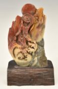Chinese carved stone figure of a immortal with script verso, on wooden stand, 18.5cm tall.