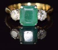 An 18ct gold ring set with an emerald cut emerald and two round cut diamonds, each approximately 0.
