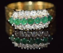 An 18ct gold ring set with a row of emeralds and two rows of diamonds with textured shoulders, 9.1g,