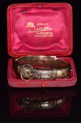 A 9ct gold buckle bangle with engraved decoration, 21.2g, 4.7 x 5.8cm, in original box