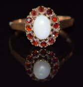 A 9ct gold ring set with an opal surrounded by garnets, 2.1g, size L
