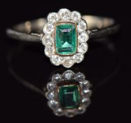 A c1920 18ct gold and platinum ring set with an emerald cut emerald surrounded by diamonds, 1.8g,