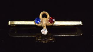 A 9ct gold brooch set with a diamond, ruby and sapphire in a clover shaped design, 2.5g, 3.5cm long