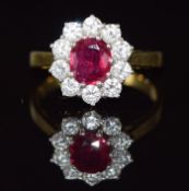 An 18ct gold ring set with a 1ct cushion cut ruby surrounded by ten round brilliant cut diamonds,