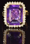 An 18ct gold ring set with an emerald cut amethyst surrounded by diamonds, 8.8g, size N