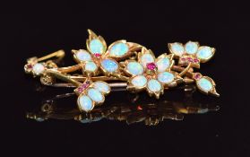 A 18ct gold brooch set with opal cabochons and rubies in a floral bouquet design, 8.8g, 5cm